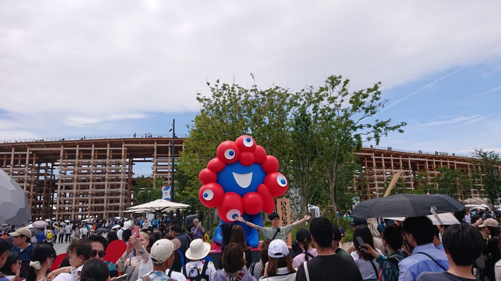 万博会場にて大屋根リングをバックにそびえるミャクミャク