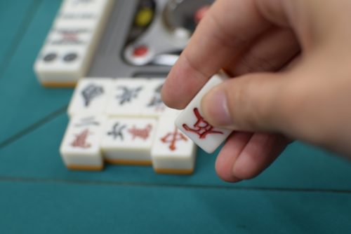 マージャン卓で牌をつもっている画像
