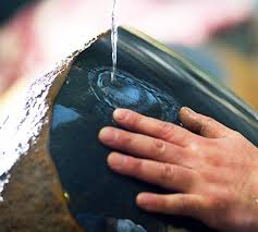 自然石の黒い面に流れる水となでる指先