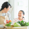 野菜の入った箱を持って母娘が微笑み合っている画像